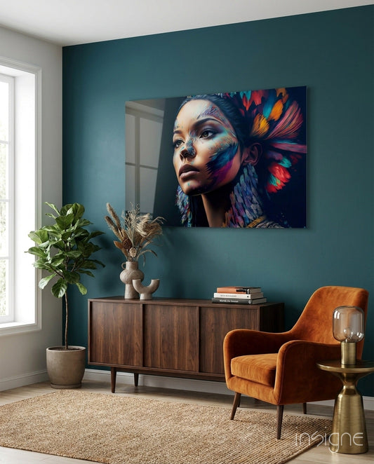 Glass wall art depicting woman with colorful feathered headdress displayed above wooden sideboard in teal room.