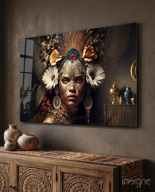 Queen of Flowers Glass Wall Art hanging above wooden cabinet, depicting woman with ornate facial tattoos, feathered headdress, and colorful bird elements in warm tones.