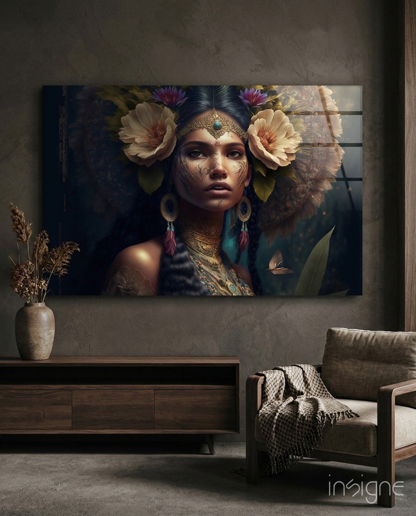 Glass wall art panel displaying a woman with ornate gold facial markings, flower crown, and feathered headdress against dark background, mounted in modern living room.