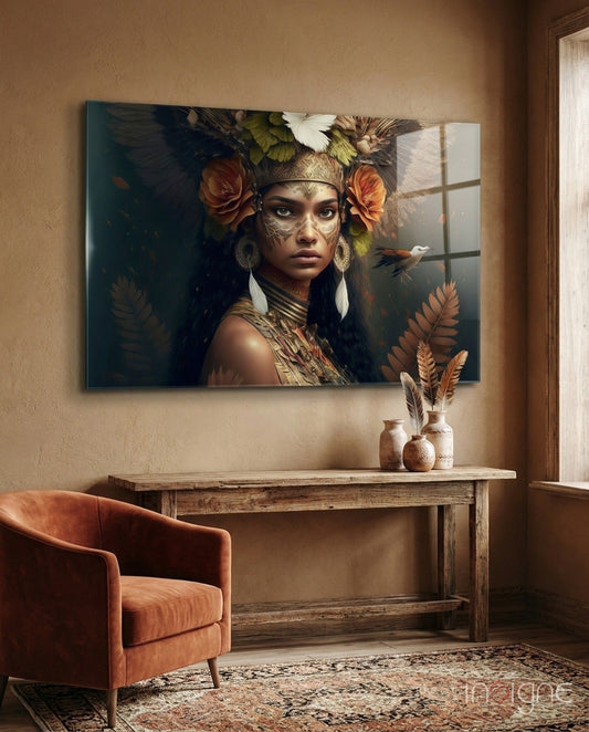 Glass wall art depicting a tribal woman with ornate headdress, facial markings, and feathered crown, displayed above wooden console table in earth-toned room.