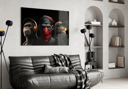Modern living room with black leather sofa displaying three stylized monkeys artwork on wall above, each wearing headphones, bandana, and earphones in black and gold tones.
