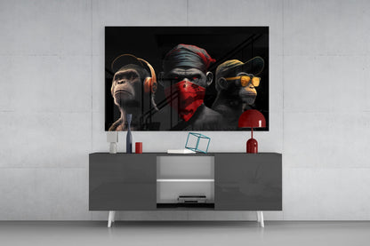 Three stylized monkeys wearing headphones, blindfold, and sunglasses displayed on a dark TV stand in a modern living room setting.