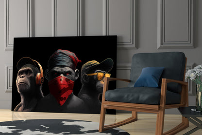 Three stylized monkeys with red and gold accents displayed on black glass panel in modern living room setting.