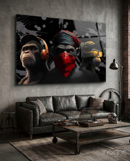 Three stylized monkeys wearing headphones and red bandana displayed as glass wall art above a leather sofa in industrial loft setting.