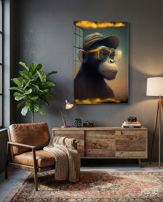 Framed glass wall art depicting a stylized chimpanzee wearing yellow-rimmed glasses and a cap, displayed above a wooden dresser in a modern interior.