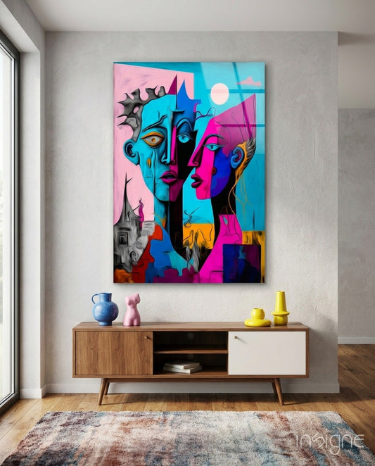 Colorful abstract faces glass wall art hanging above wooden mid-century sideboard with decorative objects and textured rug below.