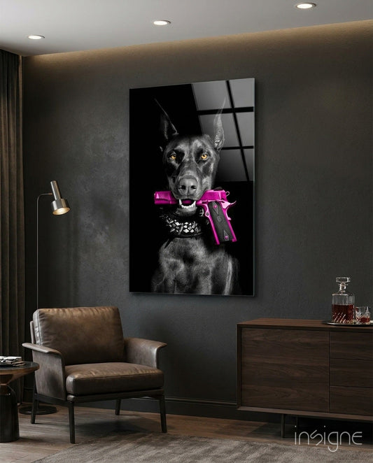 Black and white doberman with golden eyes holding pink pistol in mouth, displayed on dark wall above leather chair in modern interior.