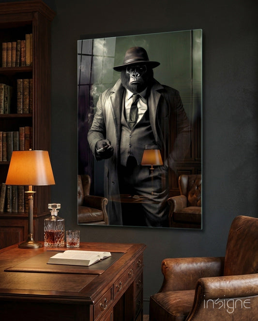 Framed glass wall art depicting a chimpanzee in business attire and fedora displayed in a wood-paneled office setting with desk, lamp, and leather furniture.