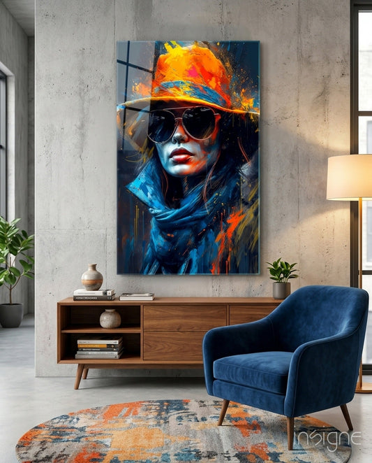 Modern living room interior featuring blue chair and wooden console table beneath vibrant portrait of woman wearing orange hat and sunglasses with blue and orange paint splashes.