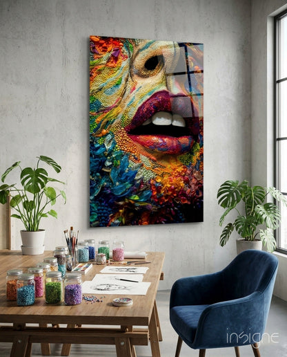 Colorful glass wall art featuring vibrant lips and coral reef textures displayed in a bright studio workspace with wooden desk and plants.