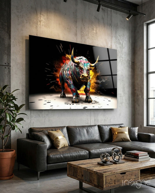 Colorful charging bull with golden horns and flame effects displayed on glass above a dark leather sofa in modern loft interior.