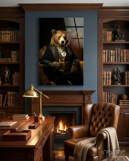 Framed glass wall art depicting an anthropomorphic bear in formal black suit holding a wine glass, displayed above a fireplace in a wood-paneled library.