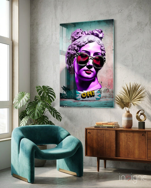 Purple and pink pop art statue head with sunglasses and "OH!" text on mint glass displayed above teal chair in modern interior.