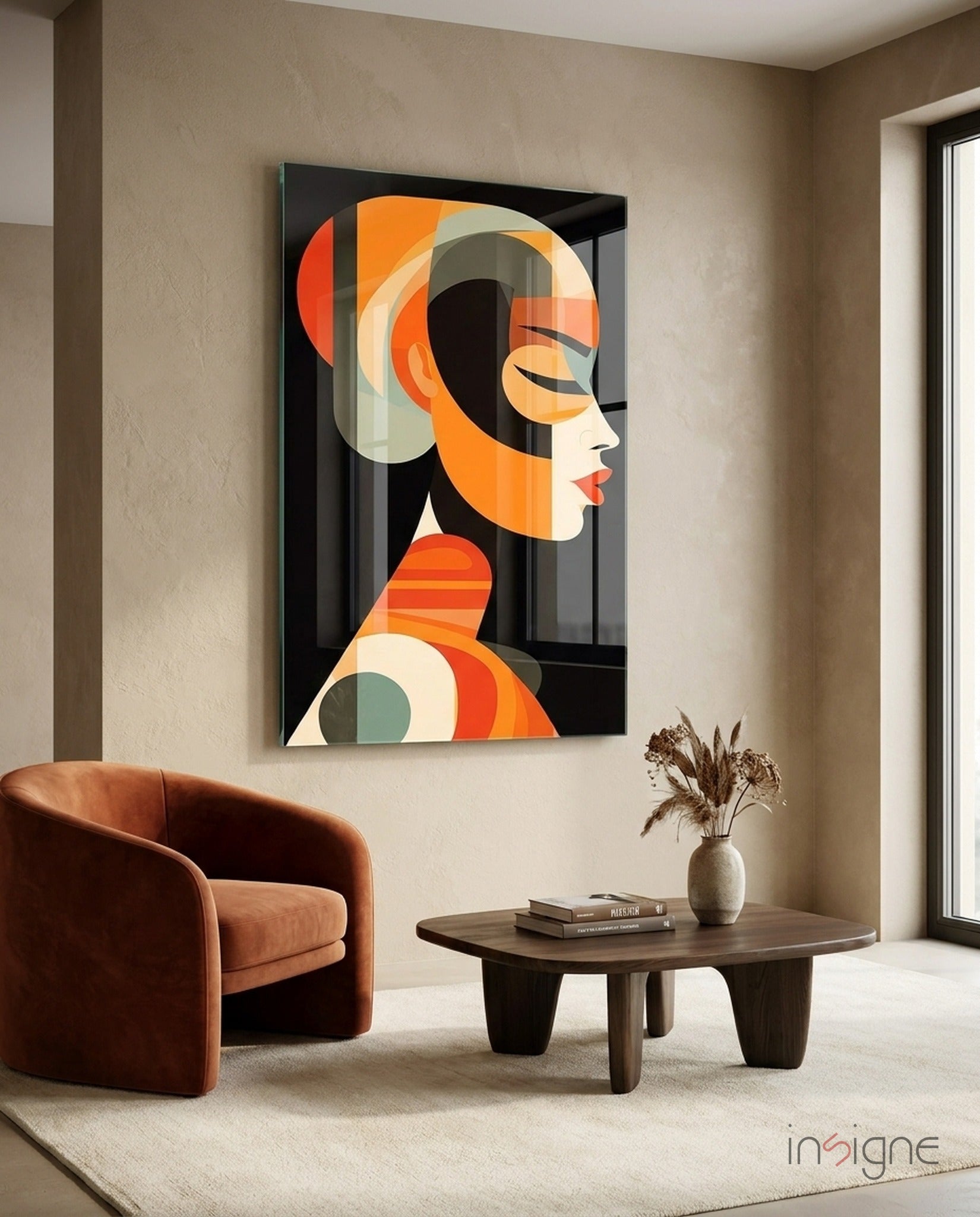 Modern interior featuring a geometric abstract portrait in orange, cream, and black on a glass wall panel above a cognac leather chair and dark wood table.