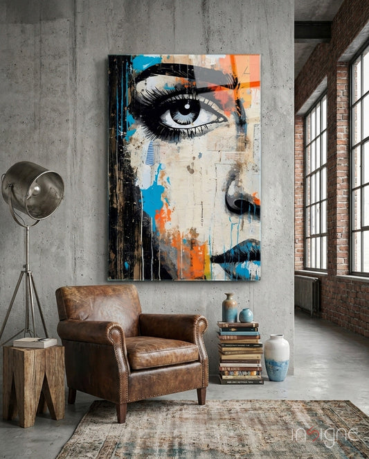 Modern industrial loft interior featuring large pop art portrait glass wall art with blue, orange, and black abstract face design above leather armchair.