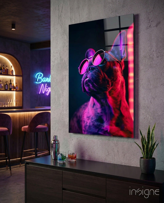 Neon bulldog artwork with round pink glasses displayed on concrete wall above dark console in modern bar setting with purple and red lighting.