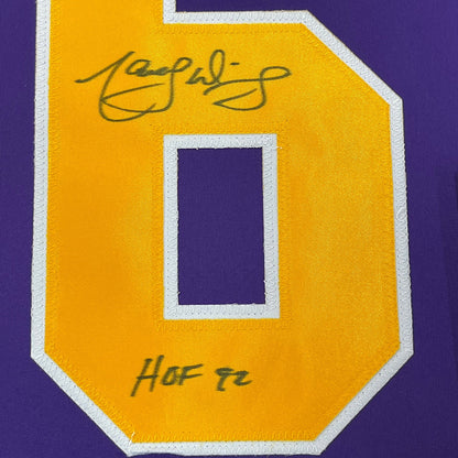 Close-up of yellow jersey patch with white border showing signed autograph and "HOF 76" text on purple fabric background.