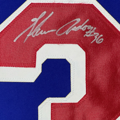Close-up detail of embroidered number 9 on red, white, and blue hockey jersey with partial signature visible above.
