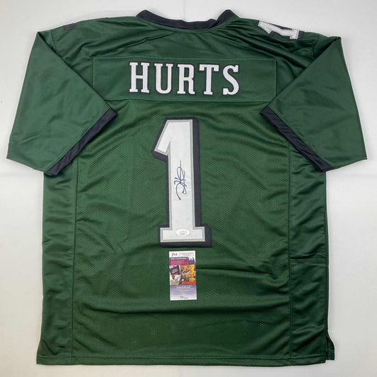 Rear view of green Jalen Hurts #1 Philadelphia football jersey with white lettering and JSA authentication sticker.