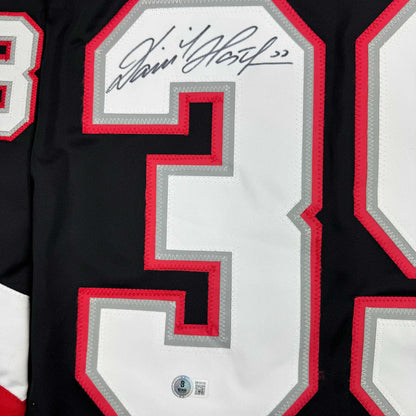 Close-up of signed number 39 on black hockey jersey with red and gray trim and Beckett authentication hologram.