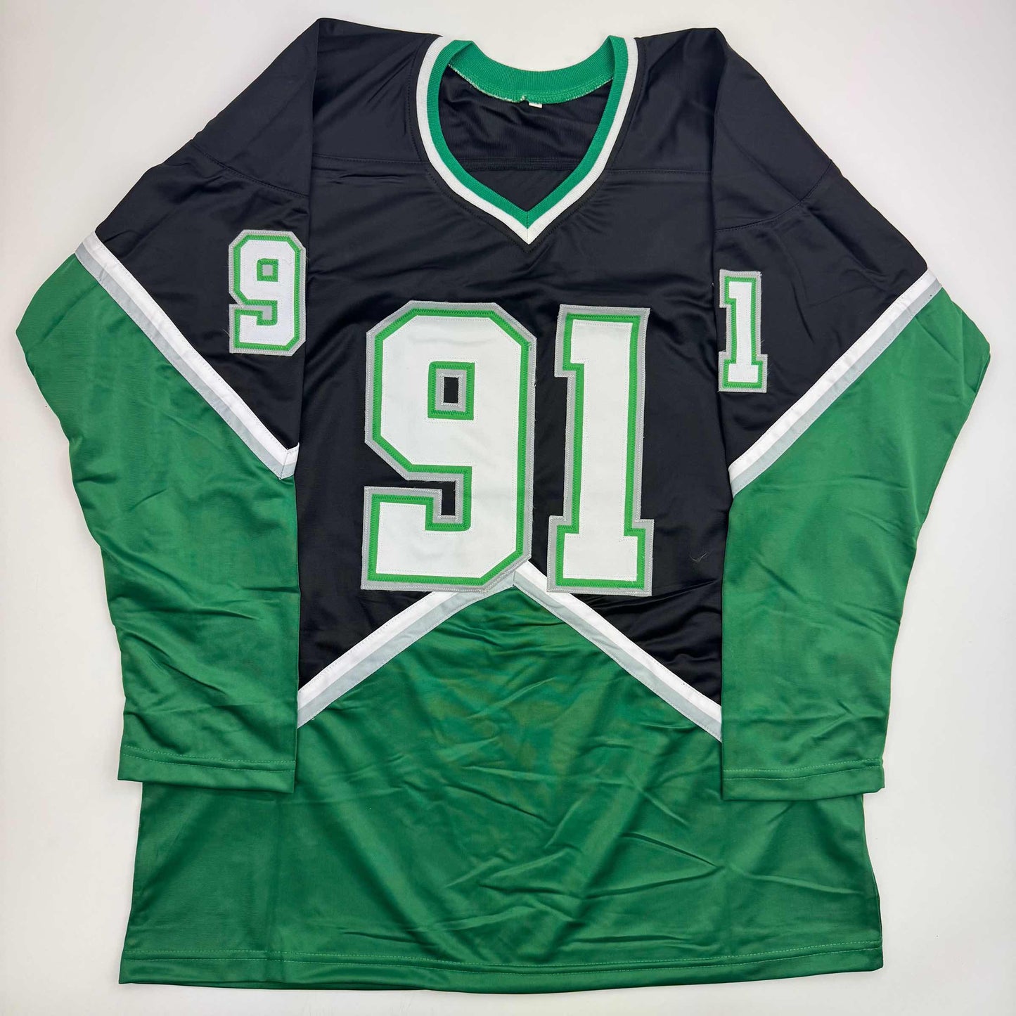 Black and green hockey jersey with white trim displaying number 91 laid flat on white background, front view.