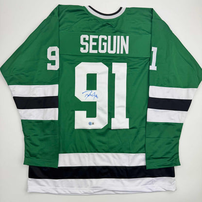Back view of green Dallas Stars hockey jersey number 91 with Seguin nameplate and blue autograph on white number.