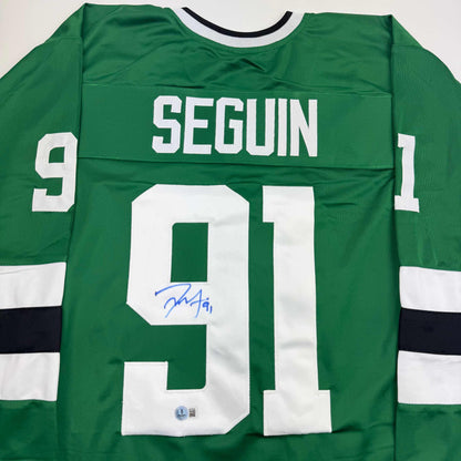 Back view of green hockey jersey with white "SEGUIN" nameplate and number 91, signed in blue ink, white and black striping on sleeves.