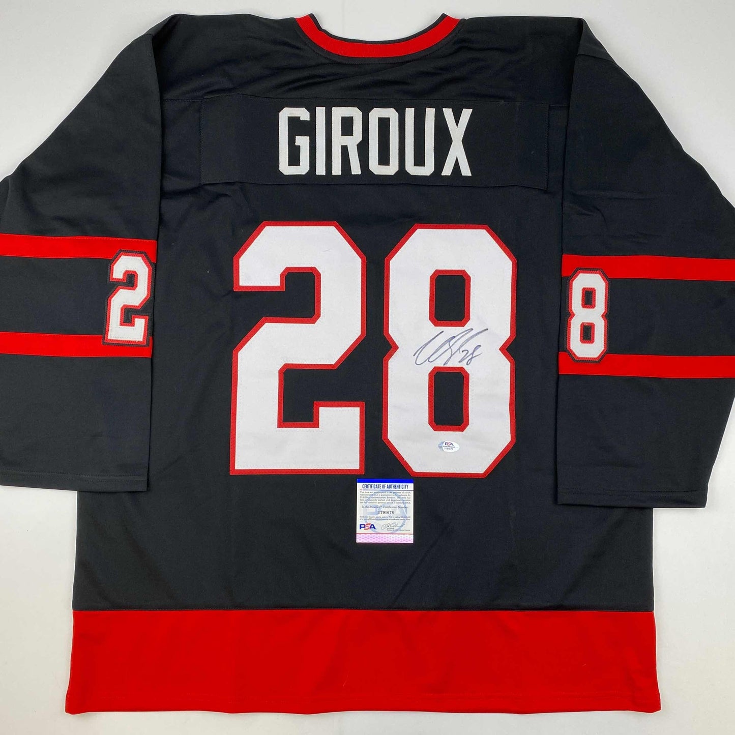 Back view of signed black hockey jersey with red and white horizontal stripes, number 28, and "GIROUX" nameplate with PSA authentication certificate.
