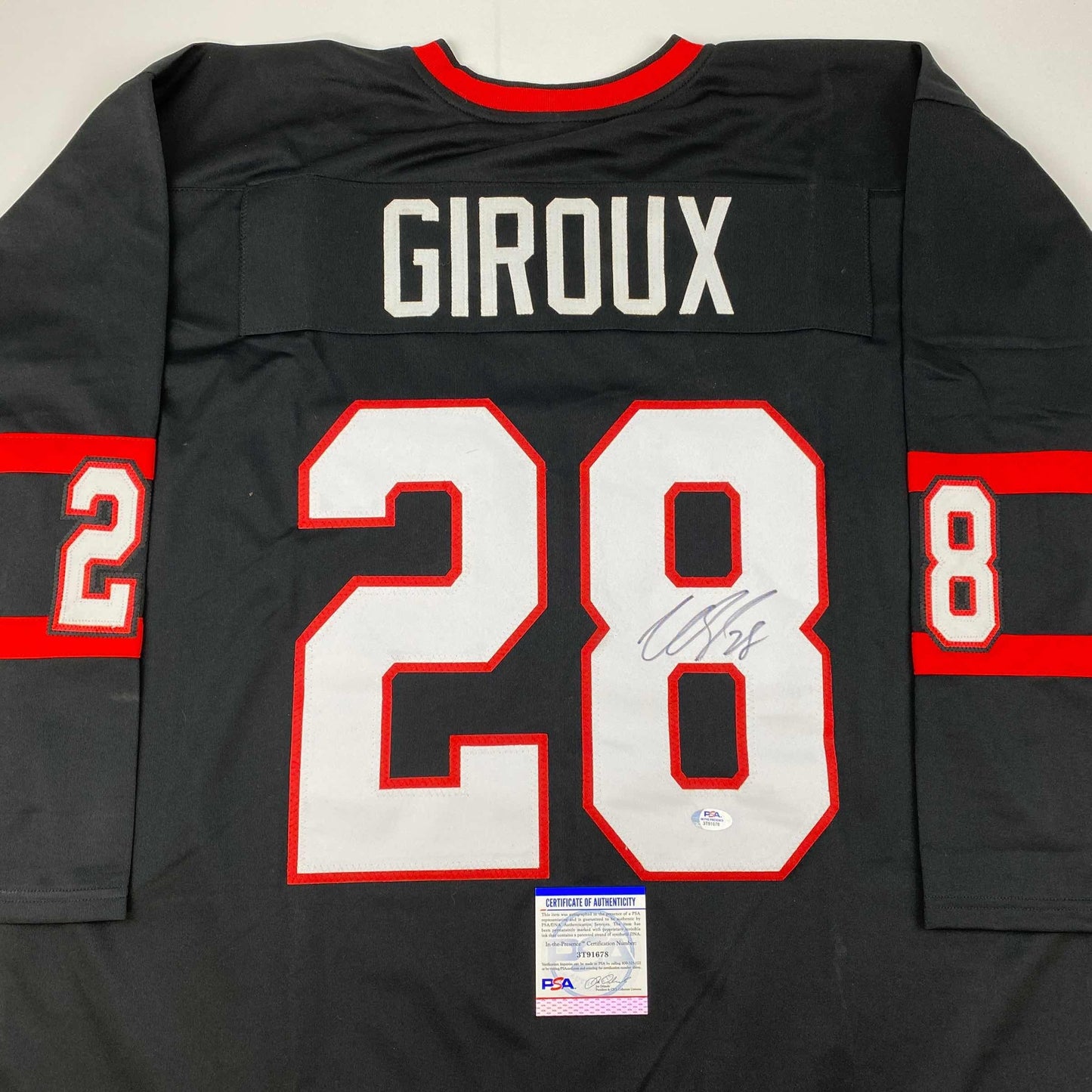Back view of black hockey jersey with red and white number 28, "GIROUX" nameplate, red neckline, and PSA authentication certificate visible at bottom.