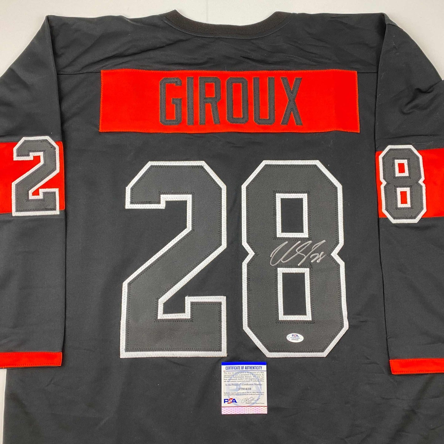 Back view of black hockey jersey with red horizontal stripe, "GIROUX" nameplate, number 28, and PSA/DNA authenticity certificate visible.