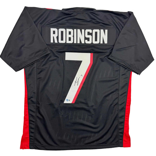 Back view of black Atlanta Falcons football jersey number 7 with red side panels, "ROBINSON" nameplate, and autograph on white number stripe.