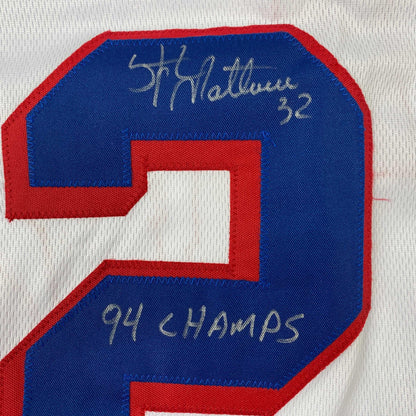 Close-up of blue and red hockey jersey number 2 with handwritten autograph and "94 CHAMPS" text on fabric.