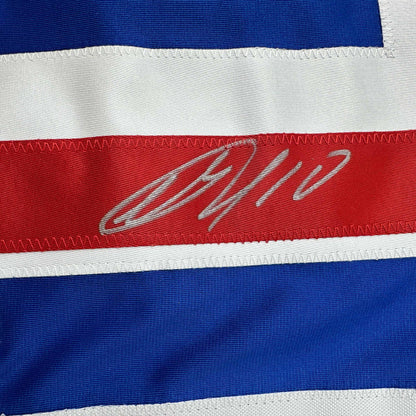 Close-up of signed red stripe on blue and white horizontally striped hockey jersey with gray cursive autograph.