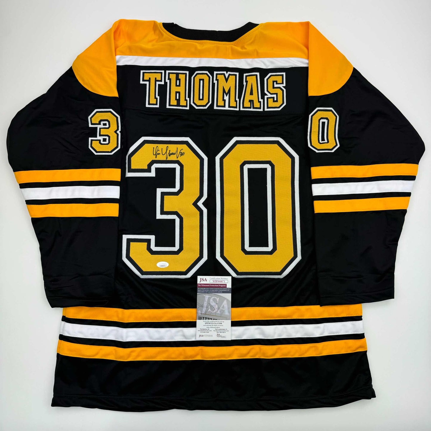 Black and gold Boston Bruins hockey jersey number 30 with THOMAS nameplate, displayed flat with JSA authentication certificate visible.