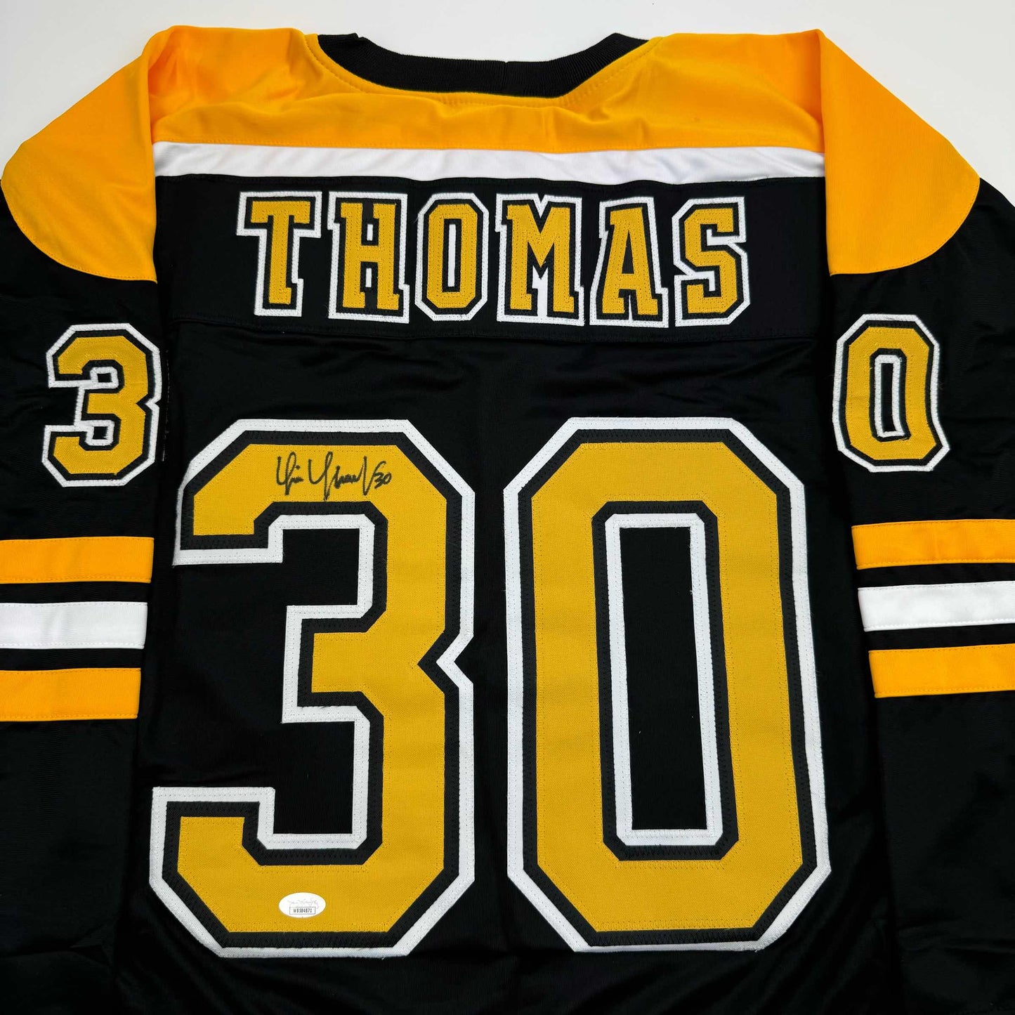 Front view of black and gold Boston Bruins hockey jersey numbered 30 with "THOMAS" across chest and autograph on number.