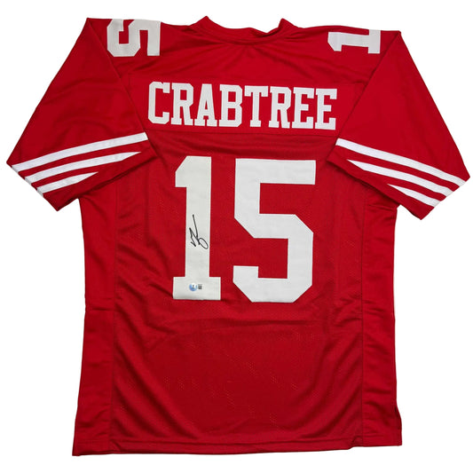 Red San Francisco 49ers football jersey number 15 with "CRABTREE" printed across chest, displayed flat with signature visible on front.