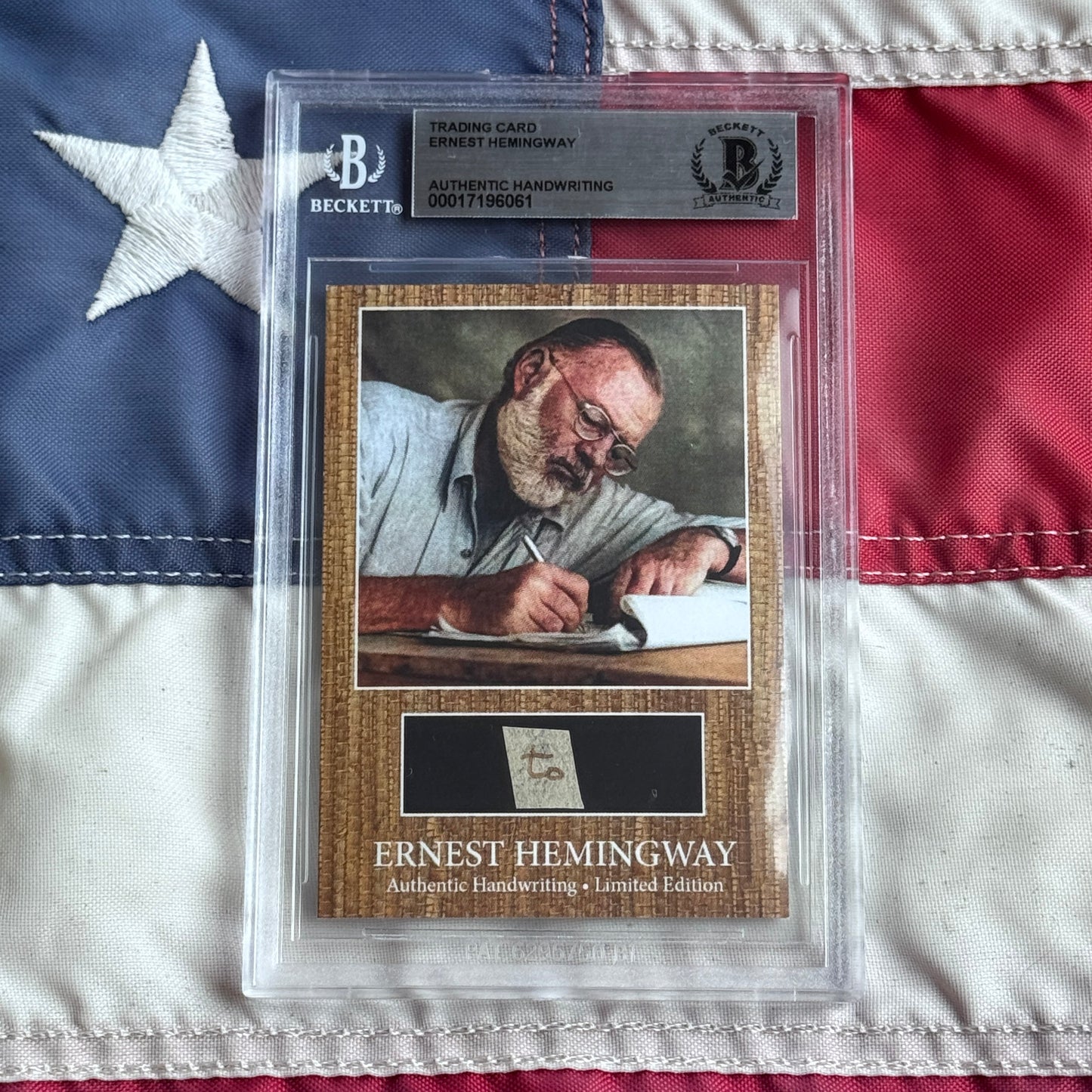Beckett authenticated Ernest Hemingway trading card with handwriting sample displayed on American flag background, showing portrait and certification details.