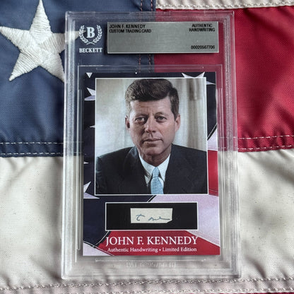 Beckett-graded trading card featuring John F. Kennedy portrait in suit and tie with authenticated signature below, displayed against American flag background.