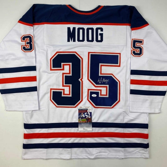 Back view of white Edmonton Oilers hockey jersey number 35 with "MOOG" nameplate, navy and red stripes, signed by player, JSA authentication certificate visible.