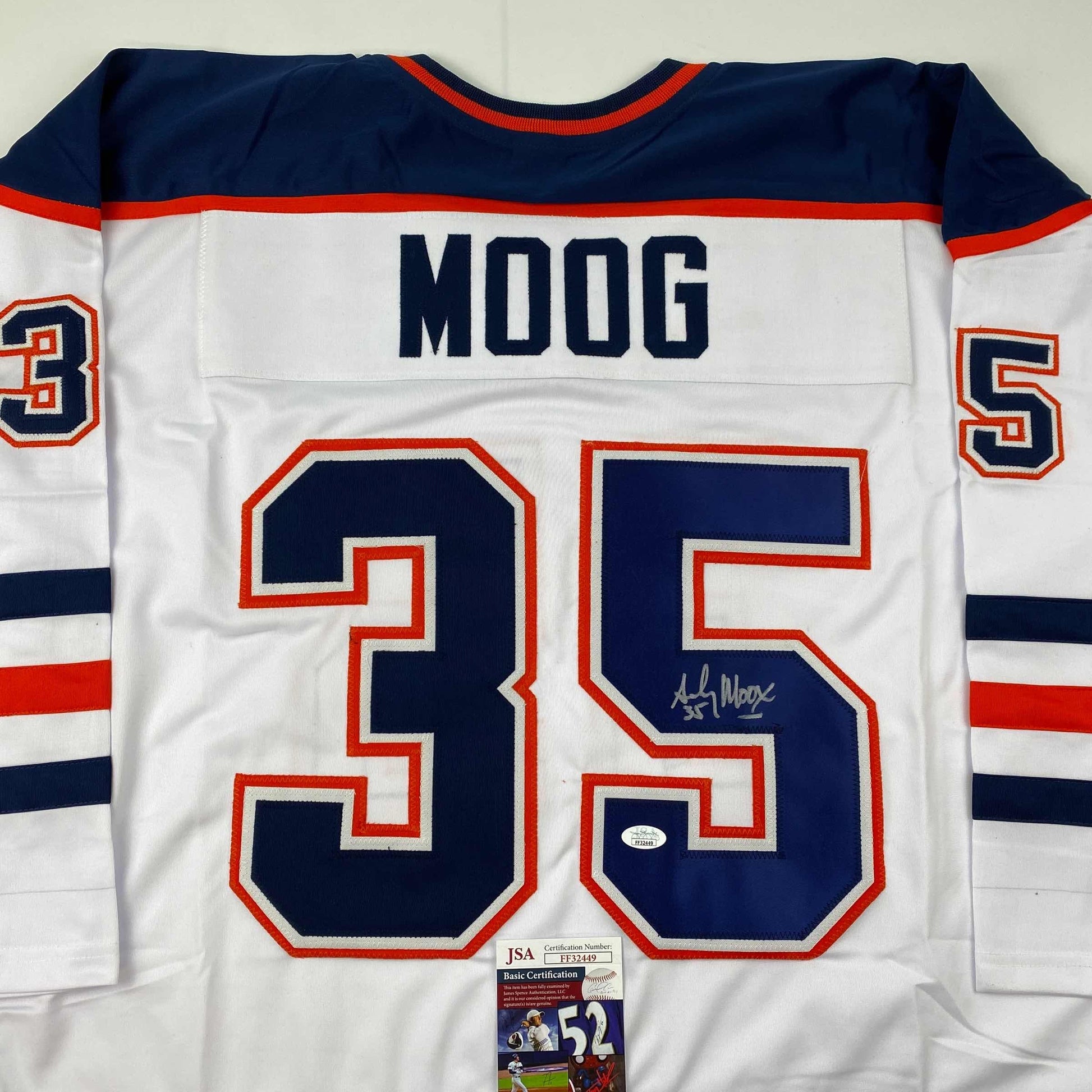 Back view of white Edmonton Oilers hockey jersey number 35 with "MOOG" nameplate and JSA authentication certificate visible at bottom.