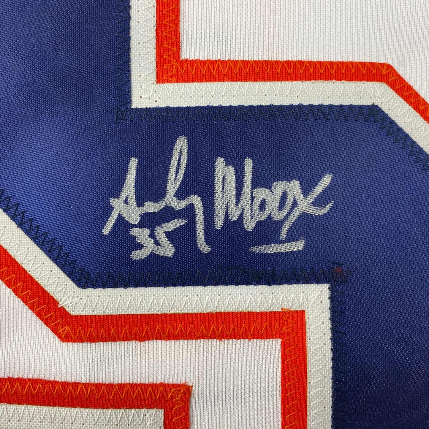 Close-up of handwritten signature on navy blue panel of white, red, and blue striped hockey jersey.