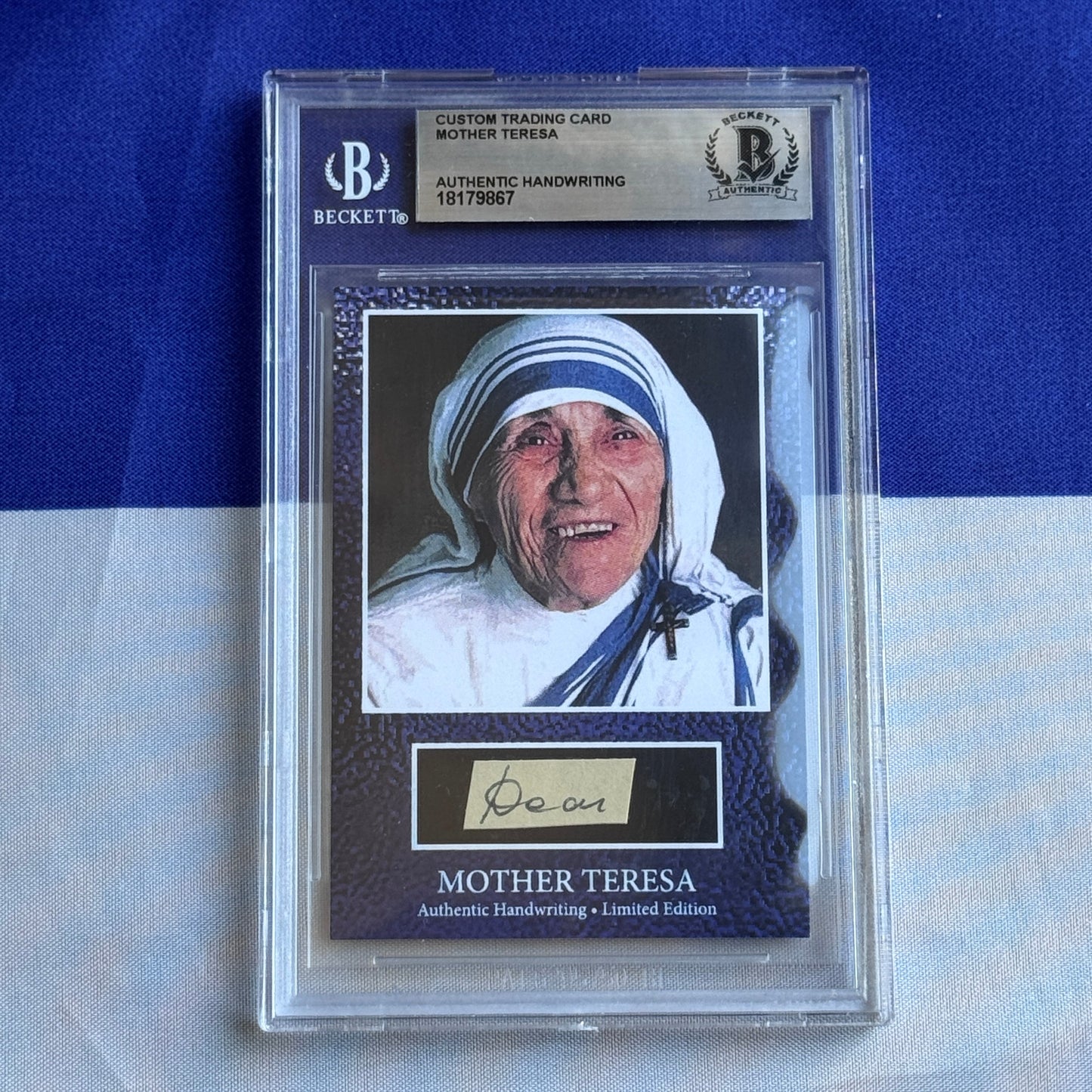 Beckett-graded trading card featuring Mother Teresa's photograph and authentic handwritten signature beneath, displayed in clear protective case against blue background.