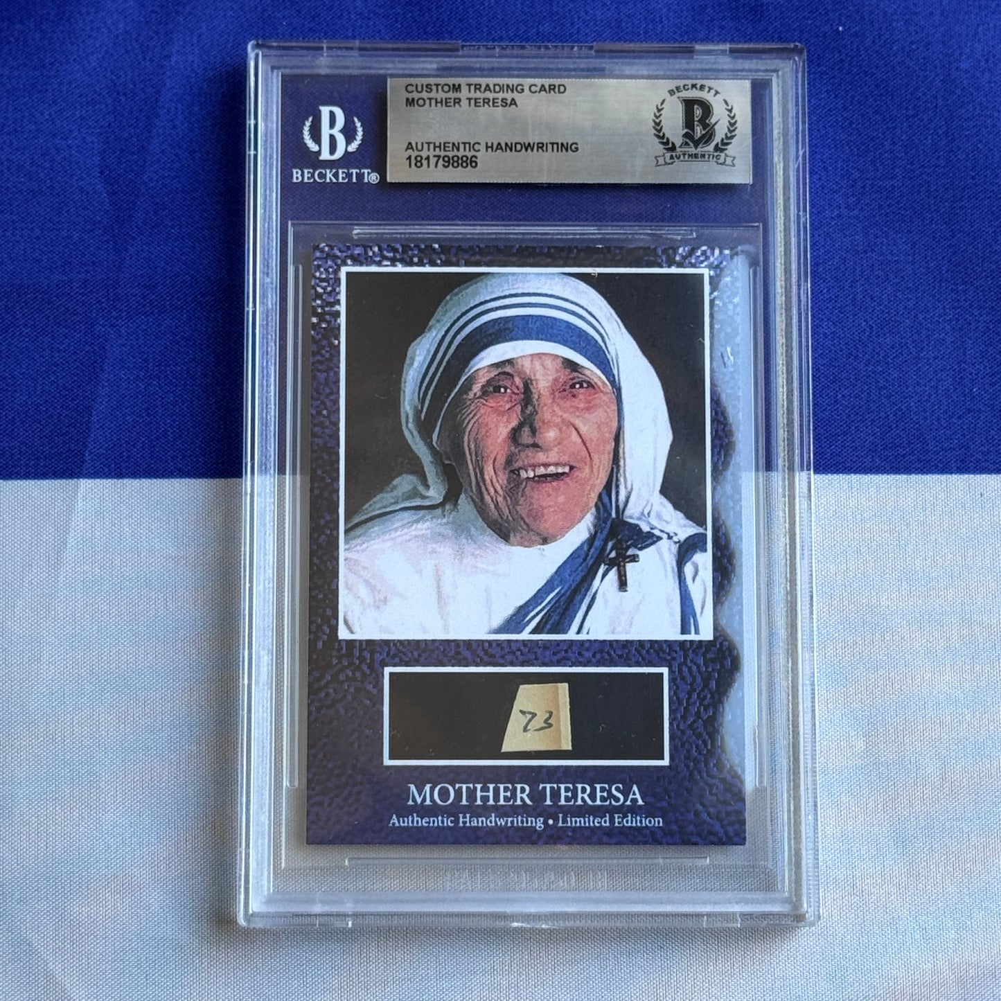 Beckett-authenticated Mother Teresa autographed trading card in clear plastic case, showing photograph of nun in white habit and blue-trimmed headpiece against blue background.