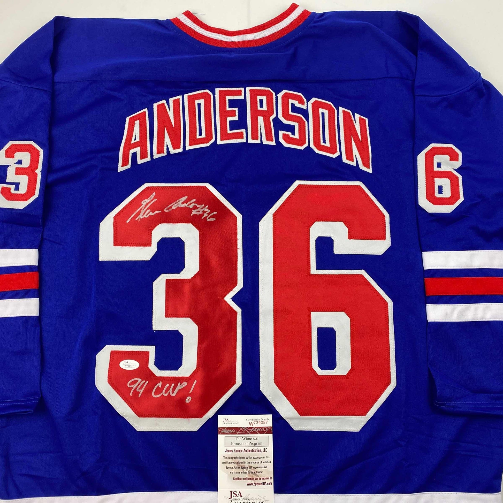 Back view of blue hockey jersey with red "ANDERSON 36" and autographed "94 Cup!" inscription, JSA authentication label visible.