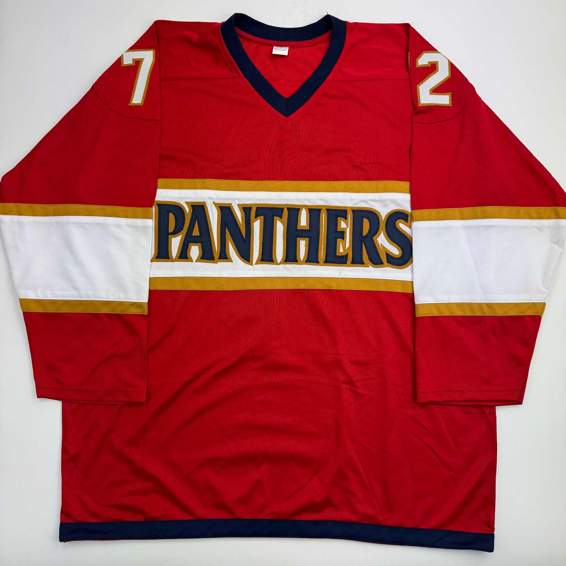 Red Panthers hockey jersey with white and gold horizontal stripes, displaying numbers 7 and 2 on shoulders, laid flat against white background.