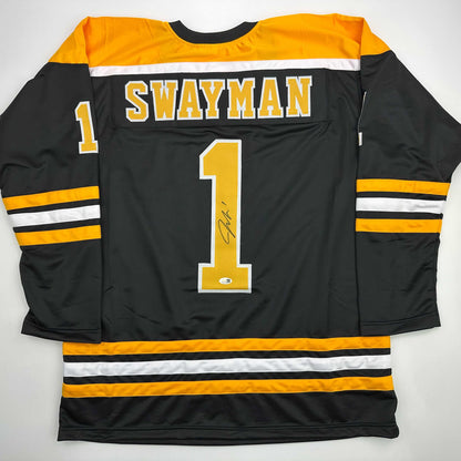 Back view of black hockey jersey with yellow and white stripes, "SWAYMAN" and number "1" with signature visible.