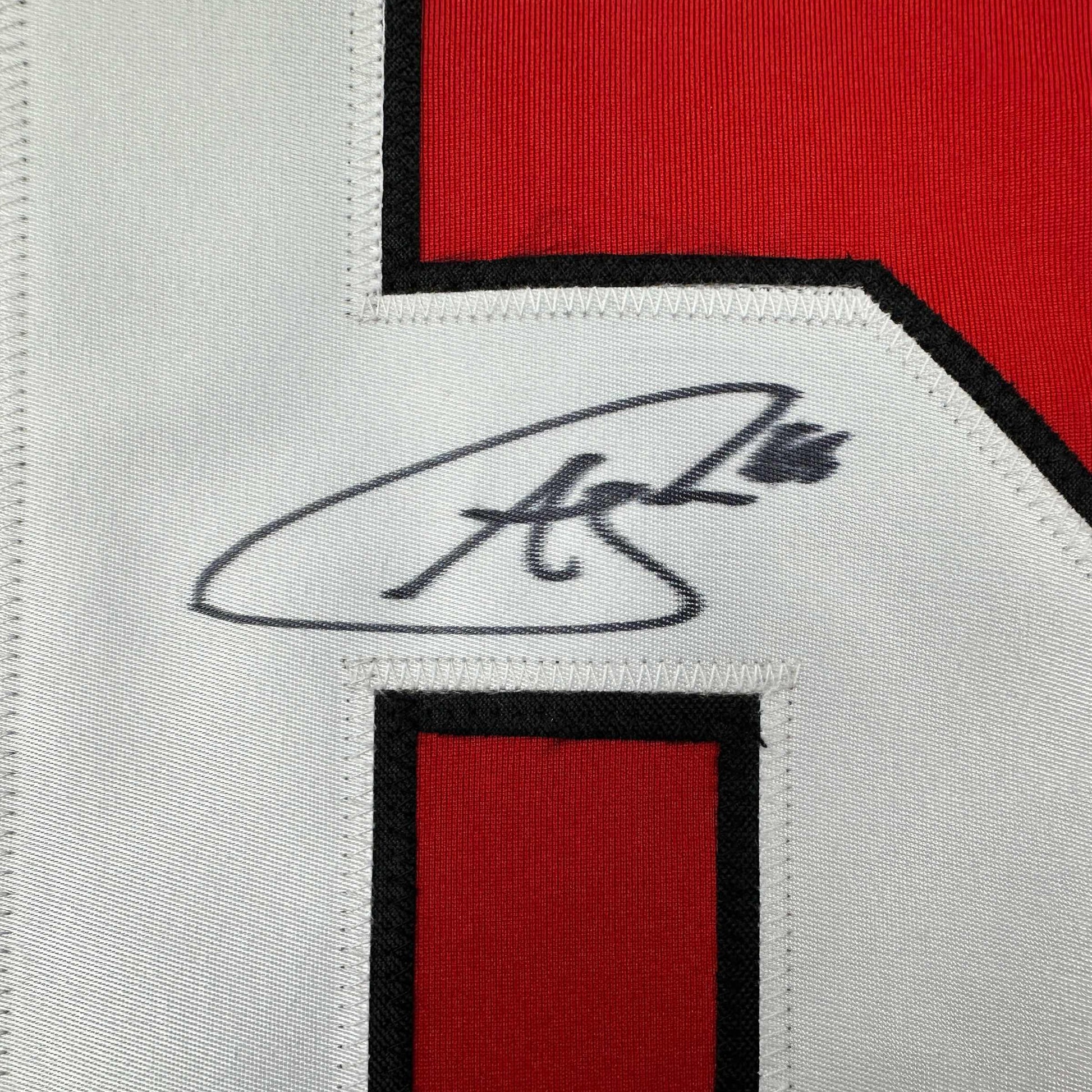 Close-up of handwritten signature on white fabric strip between red and black sections of hockey jersey.