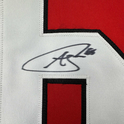 Close-up of handwritten signature on white fabric strip between red and black sections of hockey jersey.