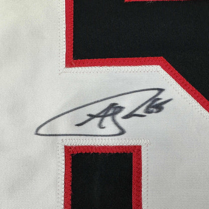 Close-up of Andrew Shaw's handwritten signature in black ink on white jersey fabric with red and black trim borders.