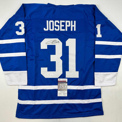 Blue Toronto Maple Leafs hockey jersey number 31 with "JOSEPH" nameplate and signature, displayed flat with JSA authentication certificate visible.